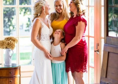 Bride and friends smiling in front of window walls