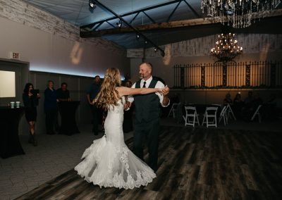 bride and father dance in dark lit room