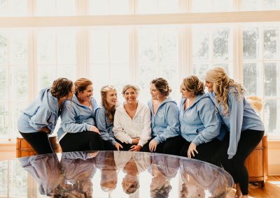 smiling bridal party sitting in a row wearing casual sweaters