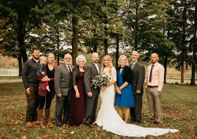 wedding couple and family pose in front of trees