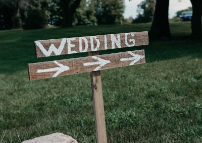 wooden wedding sign posted on grass